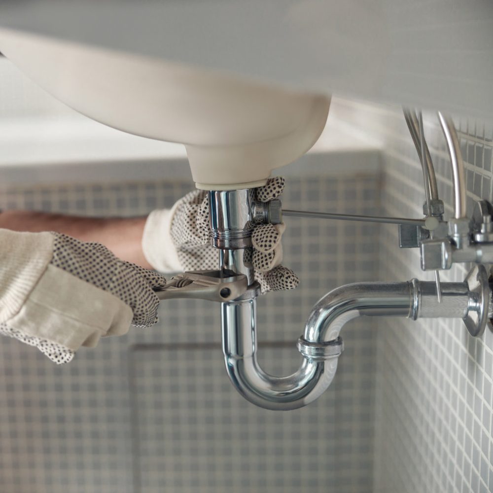 Handyman is repairing faucet of a sink at bathroom. Maintenance and household assistance concept
